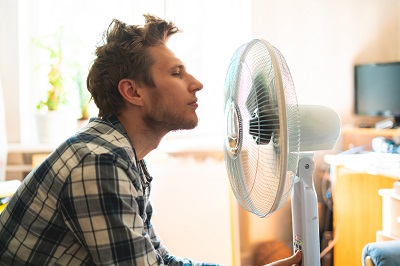 Man cooling off with a room fan Man cooling off with a room fan